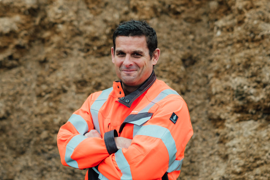 headshot of ONM Energy's Kyrone Dodd stood with his arms crossed in front of a clamp of silage ready for feeding to anaerobic digestion plant that they manage