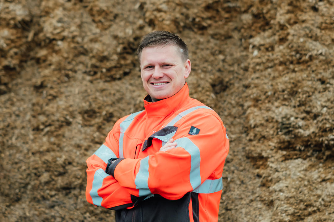 headshot of ONM Energy's Kyrone Dodd stood with his arms crossed in front of a clamp of silage ready for feeding to anaerobic digestion plant that they manage